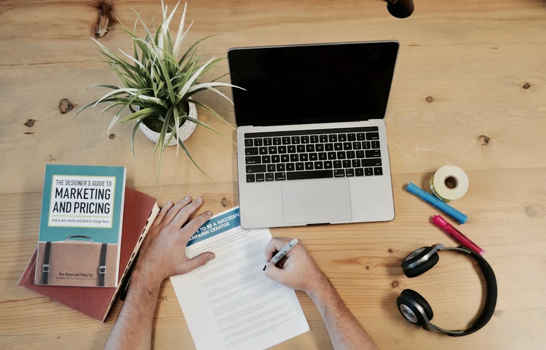 A modern workspace showing hands analyzing marketing data on a laptop and paper documents.